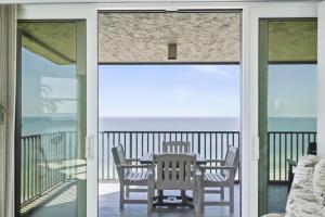 a table and chairs on a balcony with a view of the ocean at Two Bedroom Corner Condo with Panoramic Gulf Views in Clearwater Beach