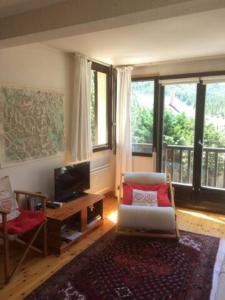 a living room with a couch and a tv and windows at Family mountain retreat with breathtaking views in Le Monêtier-les-Bains