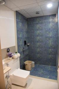 a bathroom with a toilet and a blue tiled wall at Hotel Ramayana in Ellora