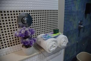 a bathroom with towels and flowers on a shelf at Hotel Ramayana in Ellora