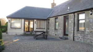 a house with a picnic table in front of it at Burnside Holiday Cottage 2 in Fochabers