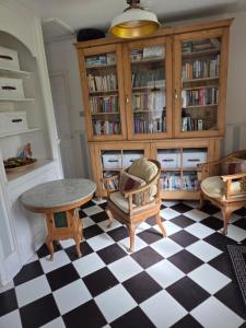 ein Wohnzimmer mit Tisch, Stühlen und Bücherregalen in der Unterkunft Firefly Studio in Holt