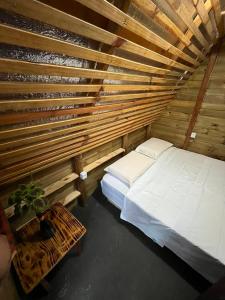 a room with a bed and a wooden wall at Hostel Caraivando in Caraíva