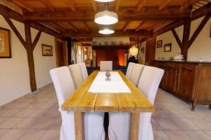 a dining room with a wooden table and white chairs at Location Le Penan in Léon