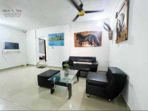 a living room with black furniture and a ceiling fan at Hotel Habitaciones D y Mar in Tolú