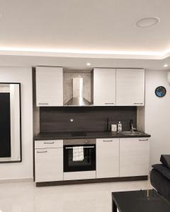 a kitchen with white cabinets and a black oven at ATK apartment in Koper