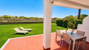 a patio with a table and chairs and a lawn at Bela Ria Waterfront House Pool & Boat to Beach in Cabanas de Tavira