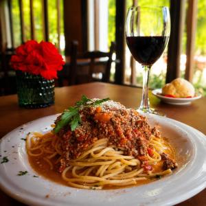a plate of spaghetti with a glass of wine at Kalken Hotel by MH in El Calafate +39 photos