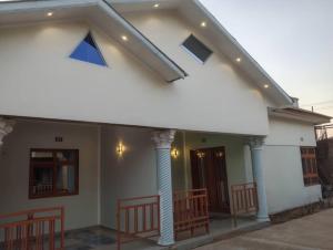 a white house with some chairs in front of it at Maisonnette KF Golf-Self Catering Apartments in Lubumbashi