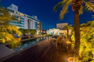 a swimming pool with a palm tree and a building at Hotel Laghetto Stilo Higienópolis in Porto Alegre