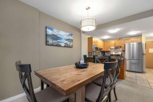 a kitchen and dining room with a wooden table and chairs at Woodrun Lodge 514 | Ski-In Ski-Out Condo w/ Pool, Hot Tub, Free Parking, Wifi & Laundry in Whistler +22 photos