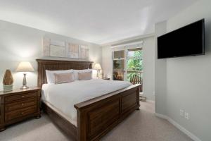 a bedroom with a large bed and a flat screen tv at Woodrun Lodge 514 | Ski-In Ski-Out Condo w/ Pool, Hot Tub, Free Parking, Wifi & Laundry in Whistler