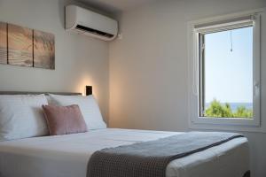 a bedroom with a large white bed with a window at Limen Port View Studio in Tinos