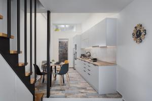 a kitchen with white cabinets and a table with chairs at Limen Port View Studio in Tinos
