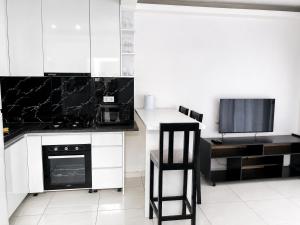 a kitchen with white cabinets and a black and white appliances at Mags GuestHouse in Praia +4 photos