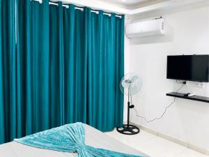 a bedroom with a blue curtain and a fan at Mags GuestHouse in Praia