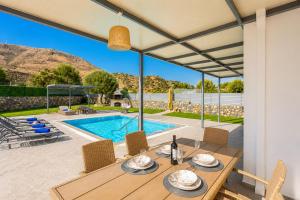 a patio with a table and chairs and a swimming pool at Villa Livis 1 in Kiotari