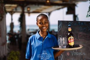 a woman holding a bottle of beer and a glass at Zenobia Beach Resort in Nungwi