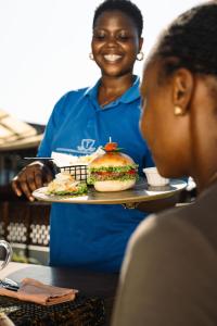 a woman holding a plate with a sandwich on it at Zenobia Beach Resort in Nungwi +16 photos