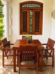 a wooden table with two chairs and a window at Agwe Villa - Hikkaduwa in Dodanduwa