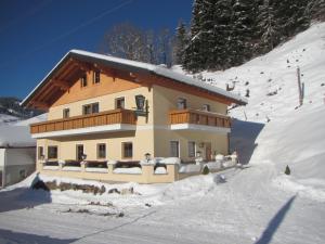a house in the snow in front of a mountain at Appartement Grubbauer in Wagrain
