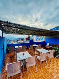 a patio with tables and chairs on a balcony at Hostel Znika Chefchaouen in Chefchaouen