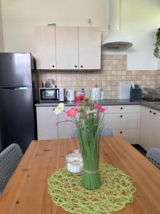 a kitchen with a wooden table with a vase of flowers at Pokoje Tanie Spanie in Zator