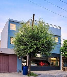 a blue building with a tree in front of it at Victory House Mty in Monterrey