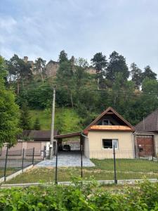 a house behind a fence with a hill in the background at Chata pod hradom in Divín