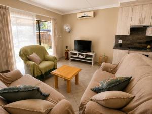 a living room with two couches and a tv at Galago Rest in Leeupoort +14 photos