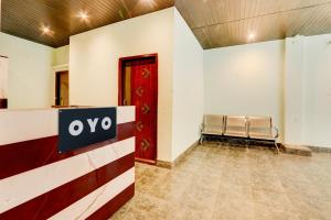 a waiting room with a bench and a red door at Hotel O Rainbow in Warangal