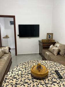 a living room with a couch and a flat screen tv at Atouli Suites in Nador