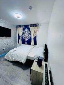 a bedroom with a bed with a blue and white curtain at Unique private rooms (1) in Bolton