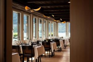 a dining room with tables and chairs and windows at Hotel Safiro in Fluelen