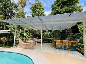 a patio with a table and a hammock next to a pool at Fauna Lodge in Drake