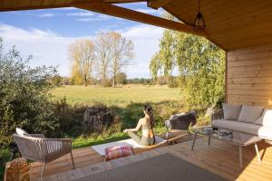 a woman sitting on a yoga mat on a deck at 110 Tiny House mit traumhaftem Blick über die Wiese in Bleckede