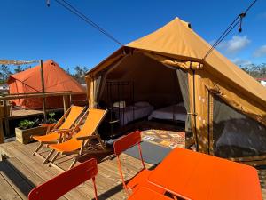 a tent with chairs and a bed in it at Parque De Campismo Orbitur Sao Pedro De Moel in São Pedro de Moel