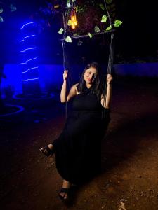 a woman in a black dress sitting on a swing at Bela Blue Stays in Bardez