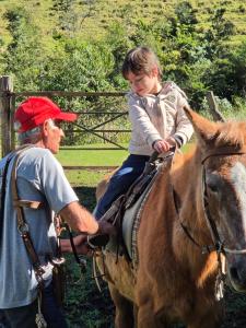 a young boy riding on a horse with a man at Big Valley Hotel Fazenda in Serra Negra