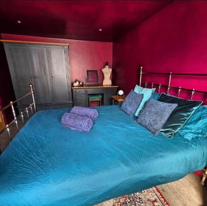 a bedroom with a blue bed with purple walls at The Wolf's Den in Patrington