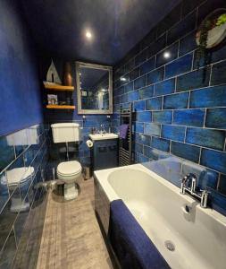 a blue tiled bathroom with a tub and a toilet at The Wolf's Den in Patrington +21 photos