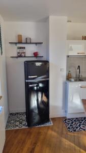 a small black refrigerator in a room with a kitchen at Chez Gabin in Tartas +3 photos