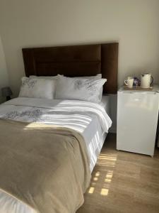 a bedroom with a large bed and a night stand at Lungi and Rendzo Guesthouse in Alberton