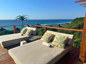 two beds on a deck with the ocean in the background at Aloha 28 in Ponta Mamoli