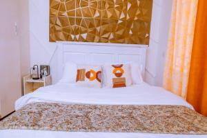 a bedroom with a white bed with two orange pillows at LyzHomes in Kampala