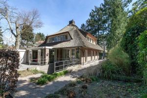 een oud huis met een rieten dak bij Exclusive villa AMS area in Hilversum