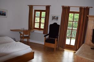 a bedroom with a bed and a desk and windows at Zum Schlosswirt in Fürsteneck