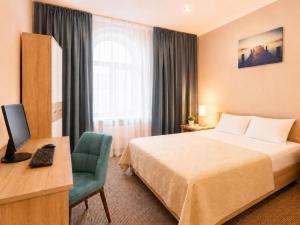 a hotel room with a bed and a desk with a computer at Nika Apart hotel in Riga