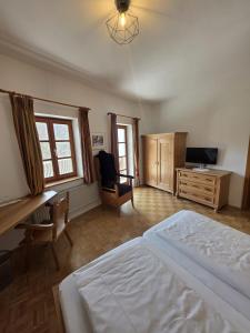 a bedroom with a bed and a desk and a television at Zum Schlosswirt in Fürsteneck