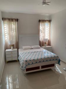 a white bedroom with a bed and two night stands at top apartments in Santo Domingo